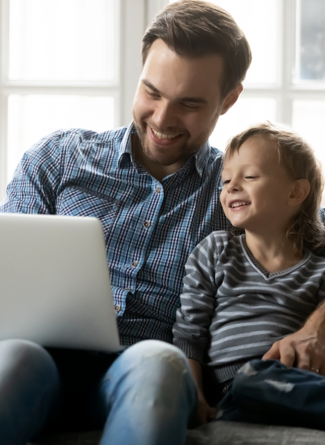 smiling father and son looking at a laptop
